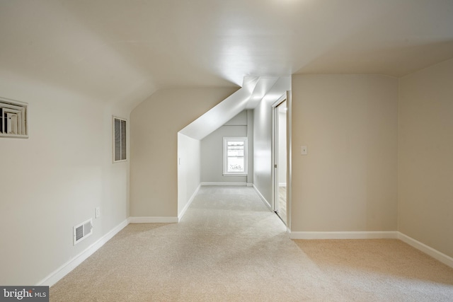 bonus room with light carpet and vaulted ceiling