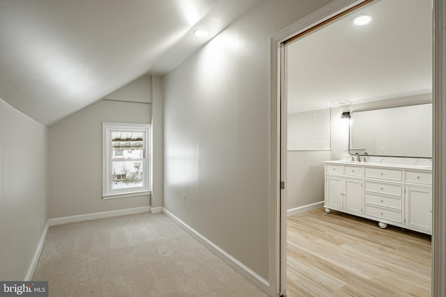 bonus room with light carpet, sink, and vaulted ceiling