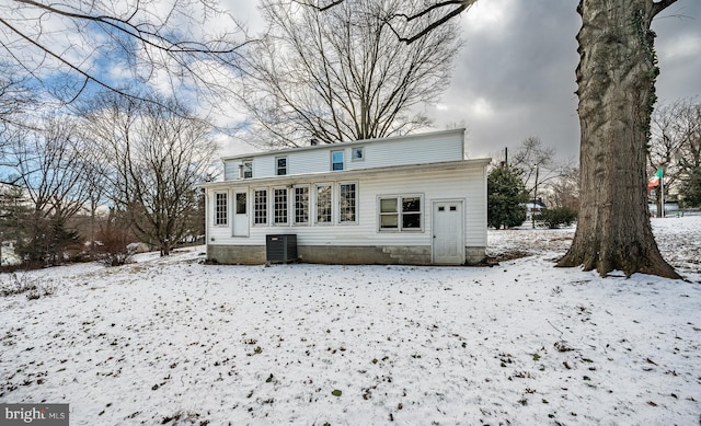 snow covered house featuring central AC unit