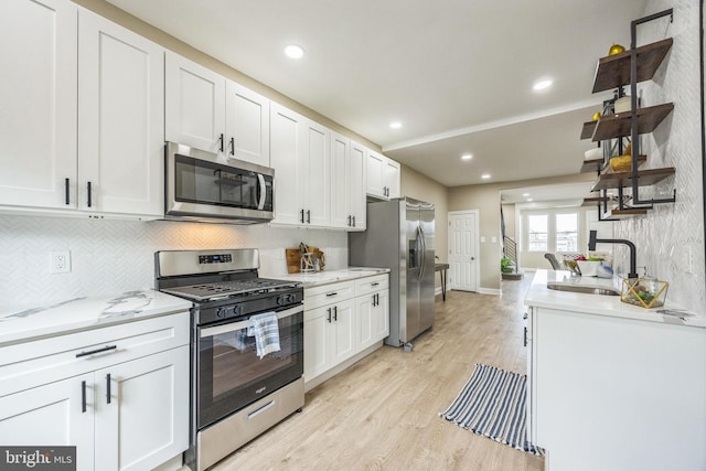 kitchen featuring white cabinets, light wood-type flooring, sink, and appliances with stainless steel finishes