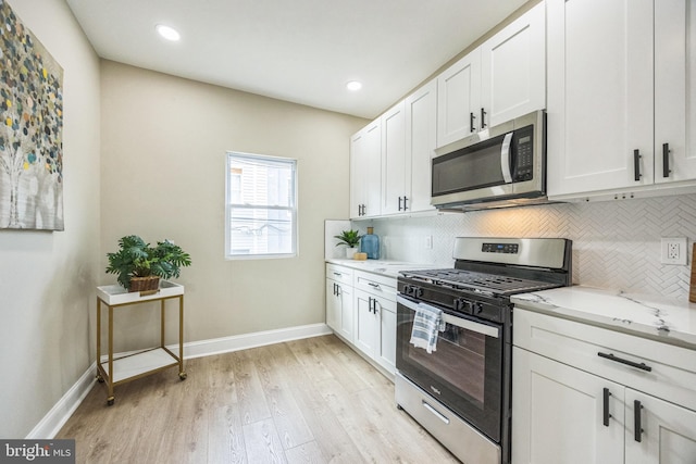 kitchen with white cabinets, light stone countertops, backsplash, and appliances with stainless steel finishes