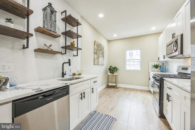 kitchen with light stone countertops, appliances with stainless steel finishes, backsplash, sink, and white cabinetry