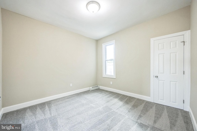 carpeted spare room featuring a baseboard heating unit