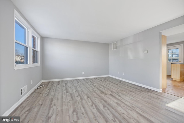 spare room featuring light wood-type flooring and plenty of natural light