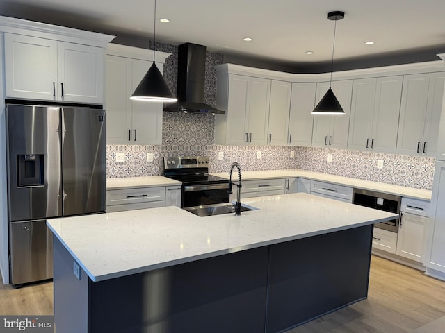 kitchen with appliances with stainless steel finishes, wall chimney exhaust hood, hanging light fixtures, and white cabinets