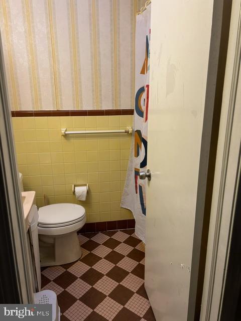 bathroom with vanity, tile walls, and toilet