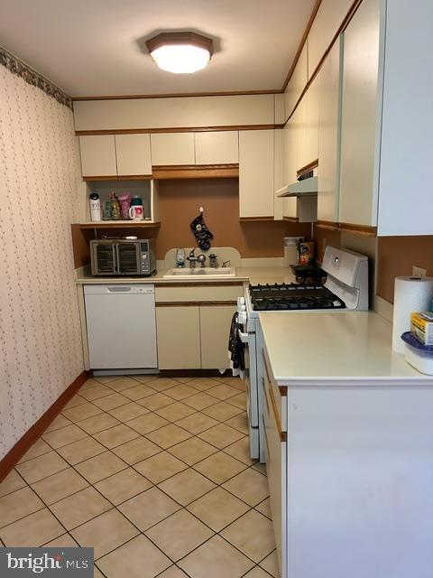 kitchen featuring light tile patterned flooring, white appliances, sink, and white cabinetry