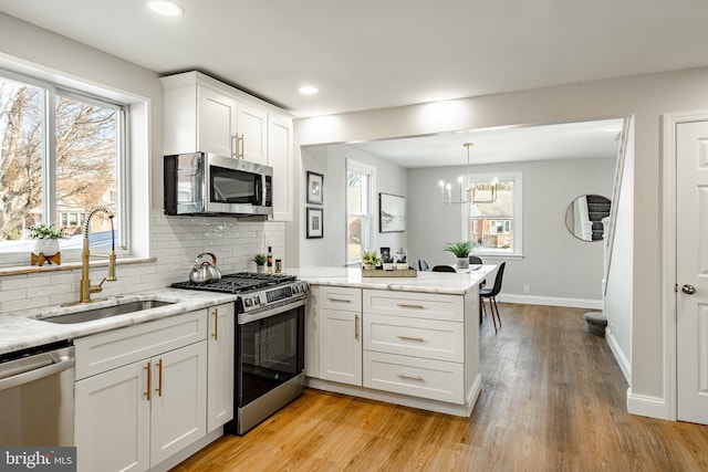 kitchen featuring kitchen peninsula, white cabinetry, sink, and appliances with stainless steel finishes