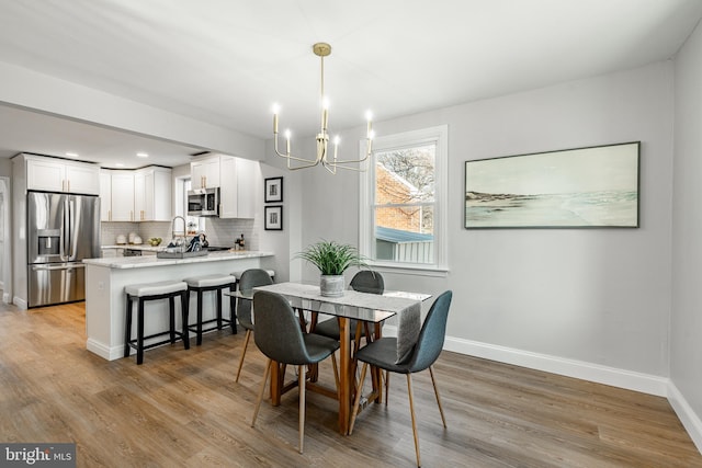 dining space with light hardwood / wood-style floors and a notable chandelier