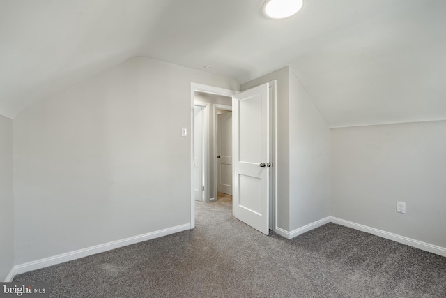 additional living space with dark colored carpet and lofted ceiling