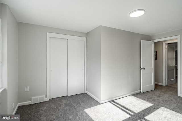 unfurnished bedroom with dark colored carpet and a closet