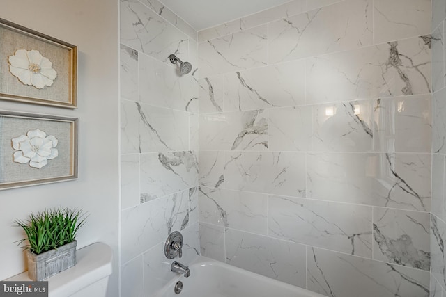 bathroom with tiled shower / bath combo and toilet