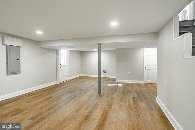 basement featuring electric panel and light wood-type flooring