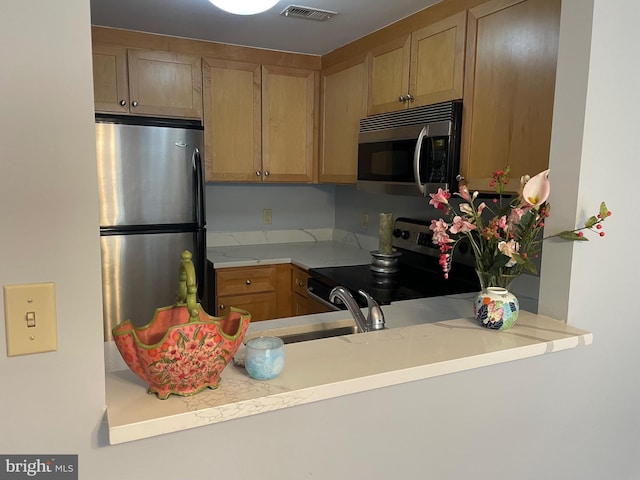 kitchen with kitchen peninsula, stainless steel appliances, and sink