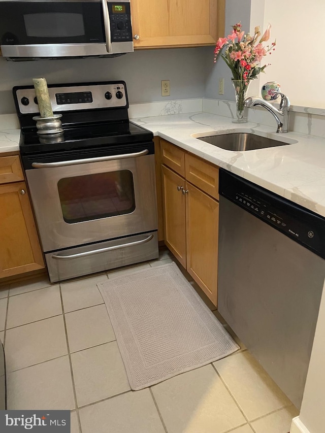 kitchen with light stone countertops, sink, light tile patterned floors, and appliances with stainless steel finishes