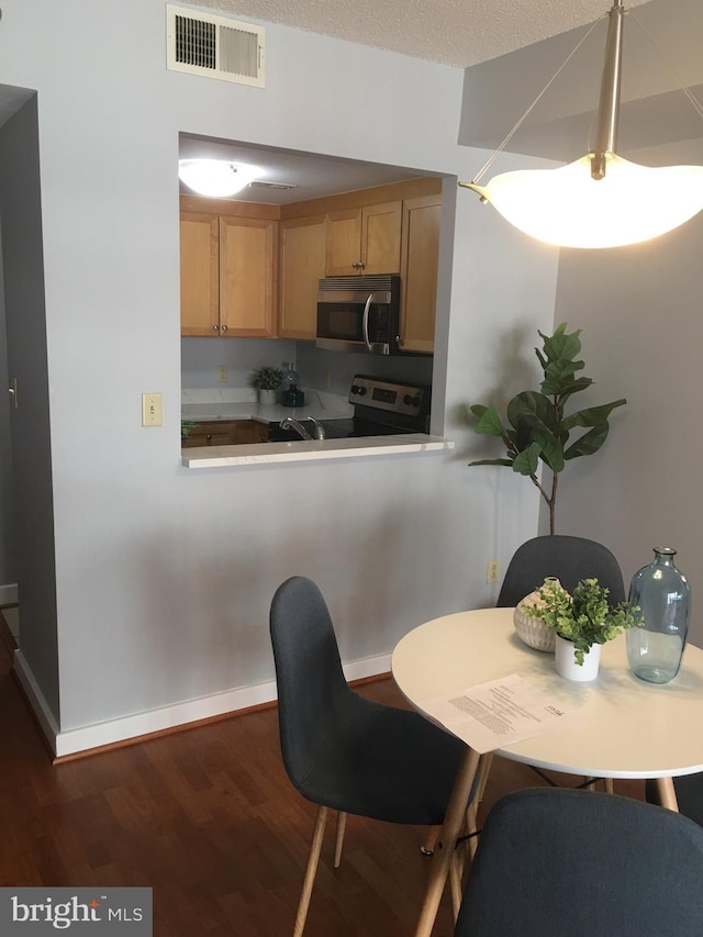 dining area with dark wood-type flooring and a textured ceiling