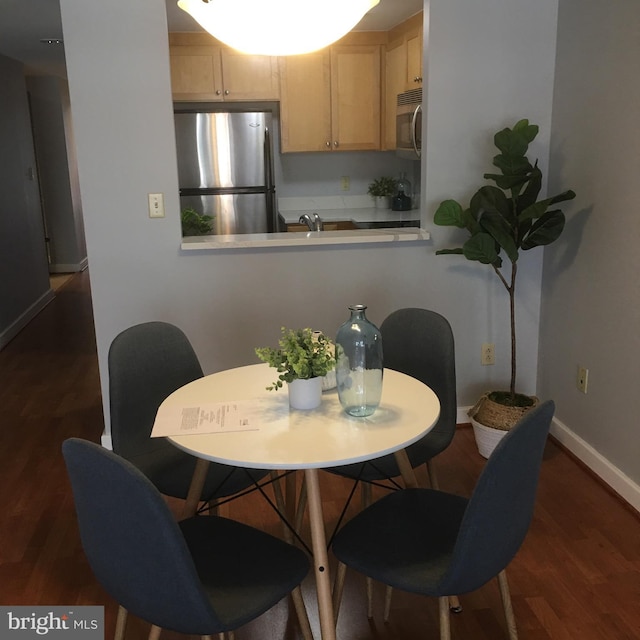 dining room with sink and dark wood-type flooring