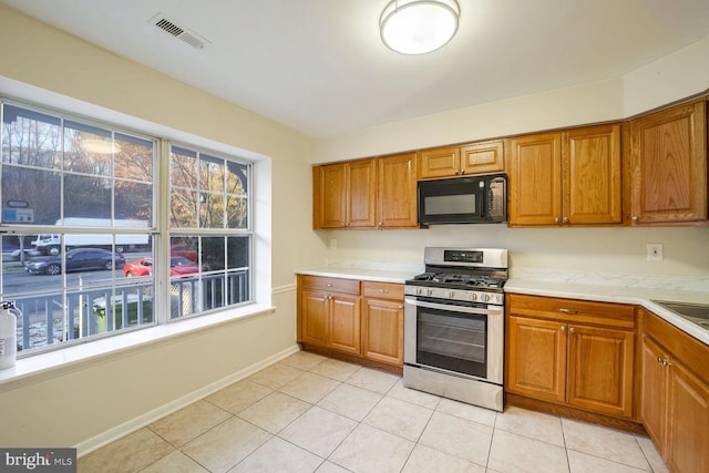 kitchen with light tile patterned floors, gas stove, and sink