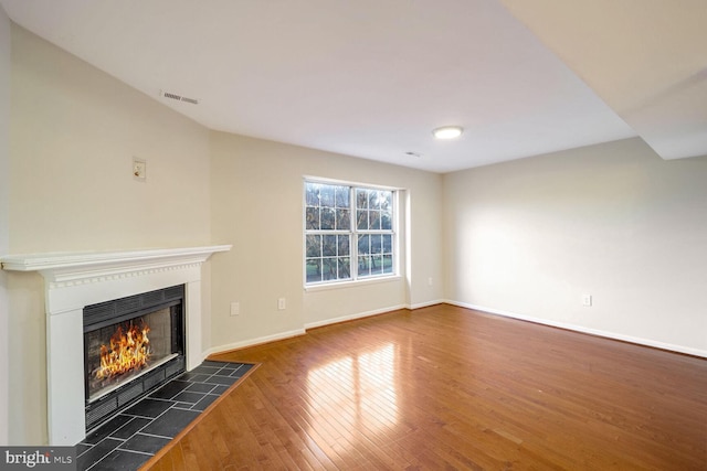 unfurnished living room featuring a tile fireplace and dark wood-type flooring