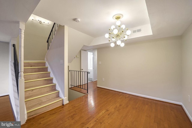 stairway with a chandelier and wood-type flooring