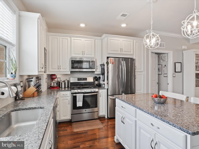 kitchen featuring a center island, hanging light fixtures, stainless steel appliances, an inviting chandelier, and white cabinets