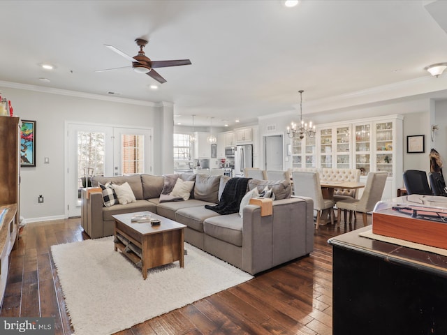 living room featuring dark wood-type flooring, ceiling fan with notable chandelier, and ornamental molding