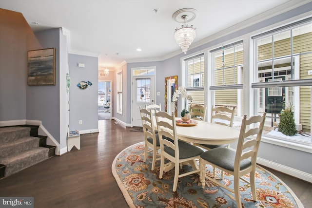 dining space with dark hardwood / wood-style floors, ornamental molding, and a notable chandelier