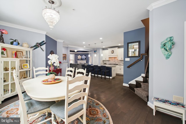 dining room featuring dark wood-type flooring, ornamental molding, and a notable chandelier