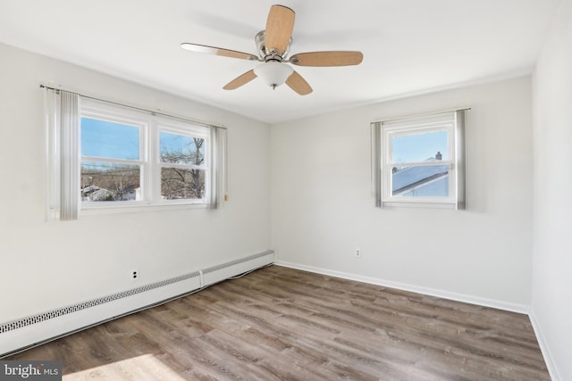 spare room featuring ceiling fan, wood-type flooring, and a baseboard heating unit