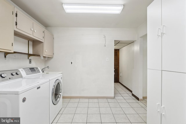 washroom featuring washing machine and clothes dryer, sink, light tile patterned flooring, and cabinets