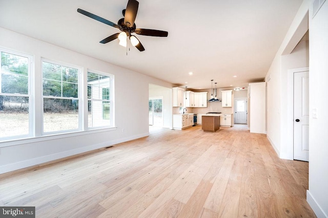 unfurnished living room featuring light hardwood / wood-style flooring, ceiling fan, and sink