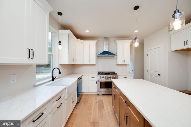 kitchen with white cabinets, stainless steel appliances, light stone counters, and wall chimney range hood