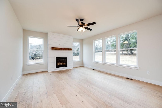 unfurnished living room with a large fireplace, light hardwood / wood-style floors, and ceiling fan