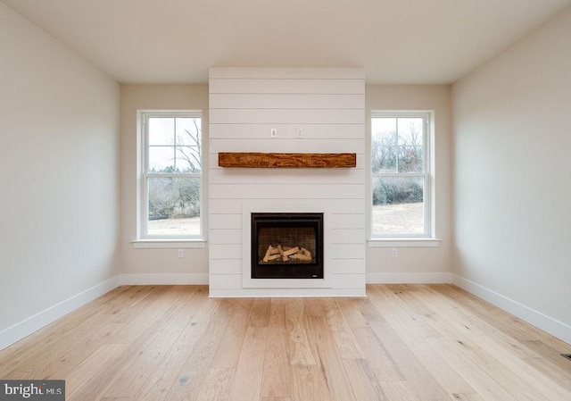 unfurnished living room with a large fireplace and light hardwood / wood-style flooring