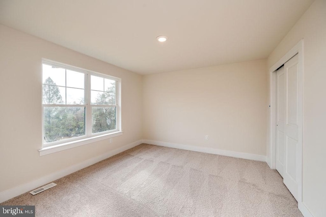 unfurnished bedroom featuring light colored carpet and a closet