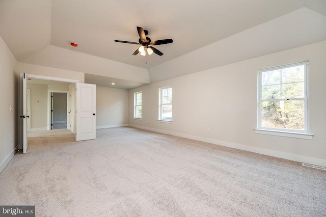 carpeted empty room with ceiling fan, a raised ceiling, and lofted ceiling