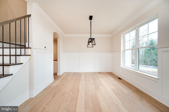 unfurnished dining area featuring plenty of natural light, light wood-type flooring, and crown molding