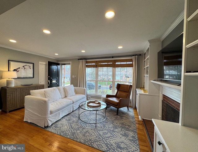 living room featuring crown molding, hardwood / wood-style flooring, and a brick fireplace