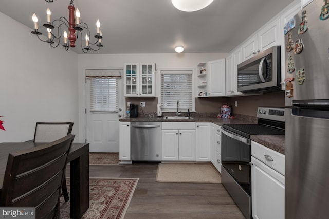 kitchen featuring sink, appliances with stainless steel finishes, dark hardwood / wood-style flooring, white cabinetry, and a chandelier