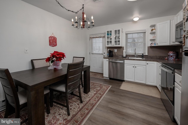 dining space with hardwood / wood-style floors, a notable chandelier, and sink