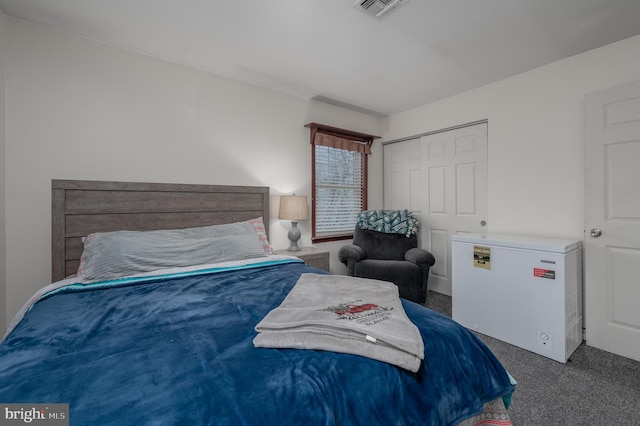 bedroom with dark colored carpet, refrigerator, and a closet