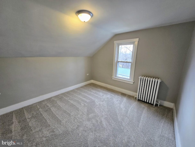 additional living space featuring carpet, radiator heating unit, and vaulted ceiling