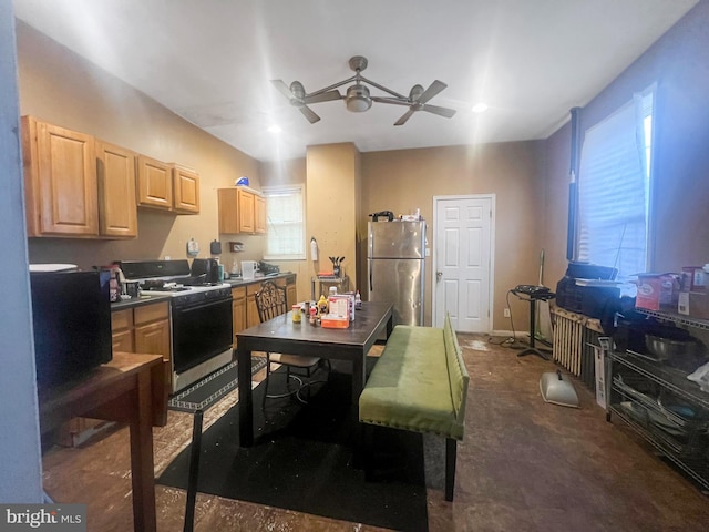 kitchen featuring light brown cabinetry, white gas range oven, stainless steel refrigerator, and ceiling fan