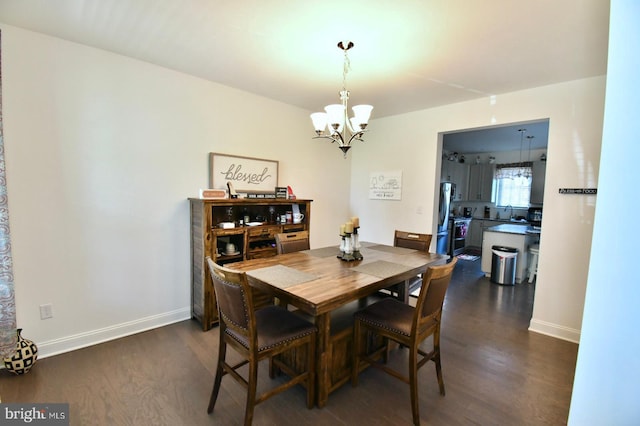 dining space featuring sink, dark wood-type flooring, and a chandelier