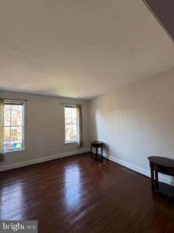 spare room featuring dark hardwood / wood-style flooring and plenty of natural light