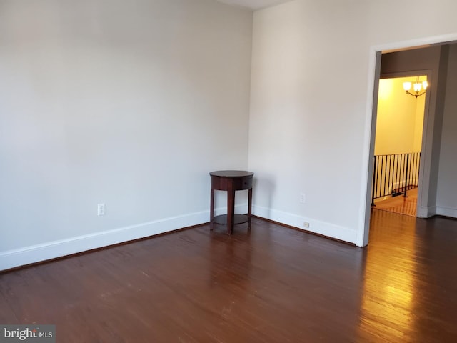 spare room with dark hardwood / wood-style flooring and a notable chandelier