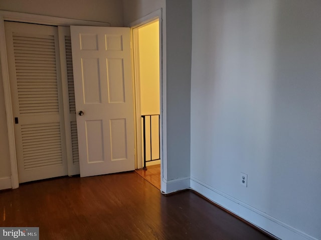 unfurnished bedroom featuring a closet and dark wood-type flooring