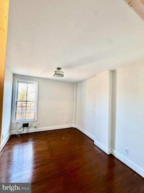 unfurnished room with dark wood-type flooring