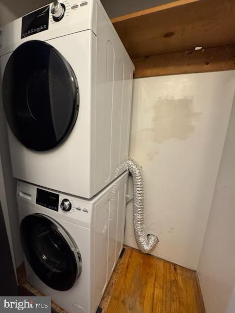 washroom with stacked washer / drying machine and hardwood / wood-style flooring