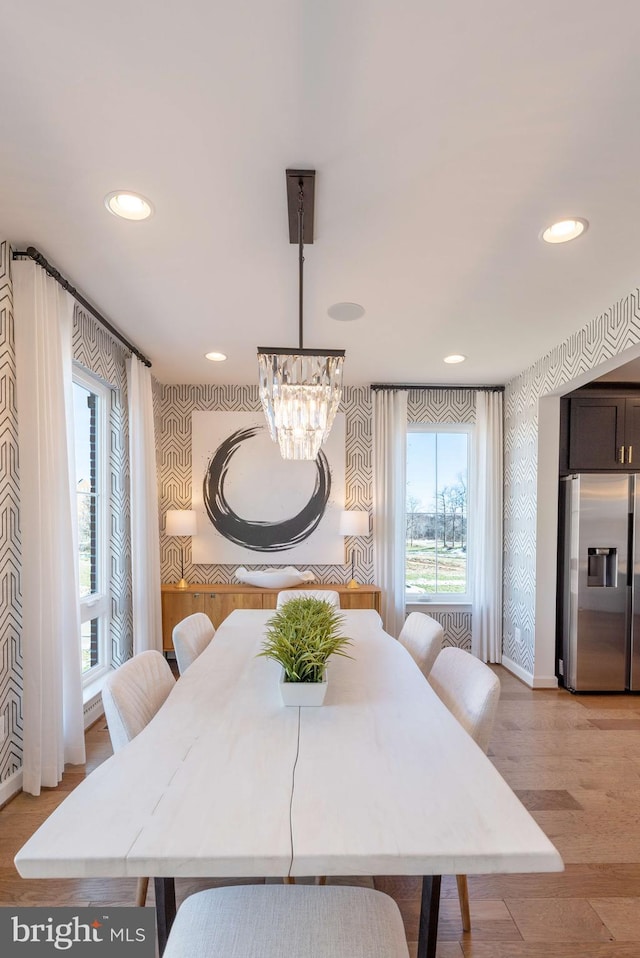 dining space with light hardwood / wood-style floors and an inviting chandelier